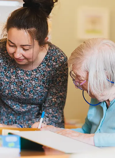 Young staff assisting elderly resident with activity at Lancashire care home
