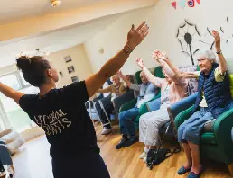 Woman leading seated exercise class for residents at High Brake House, Ribble Valley