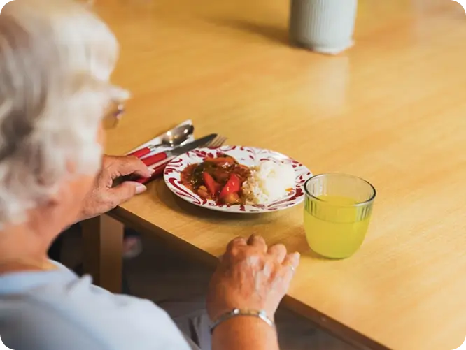 Elderly resident enjoying a meal with vegetables in a welcoming Lancashire care home