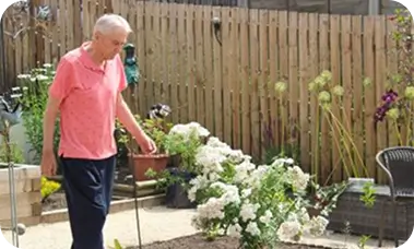 Older man using a walking stick in a care home garden in Lancashire