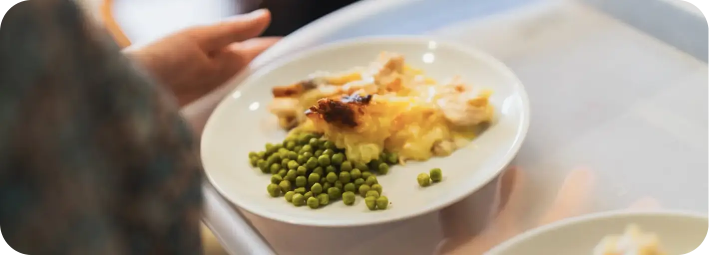 Plate of peas and baked casserole served in a Clitheroe care home