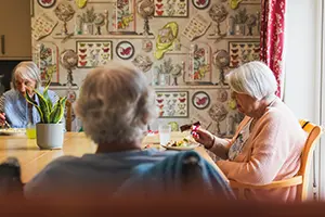 Three elderly women sharing meal at dining table in High Brake House, Lancashire care home